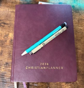 Image shows a closed 2026 planner by ChristianPlanner with pens resting on top.
